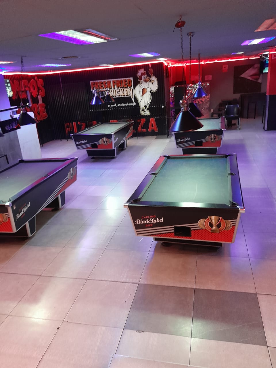Pool tables beneath pendant lights at Cheeky Tiger Randburg