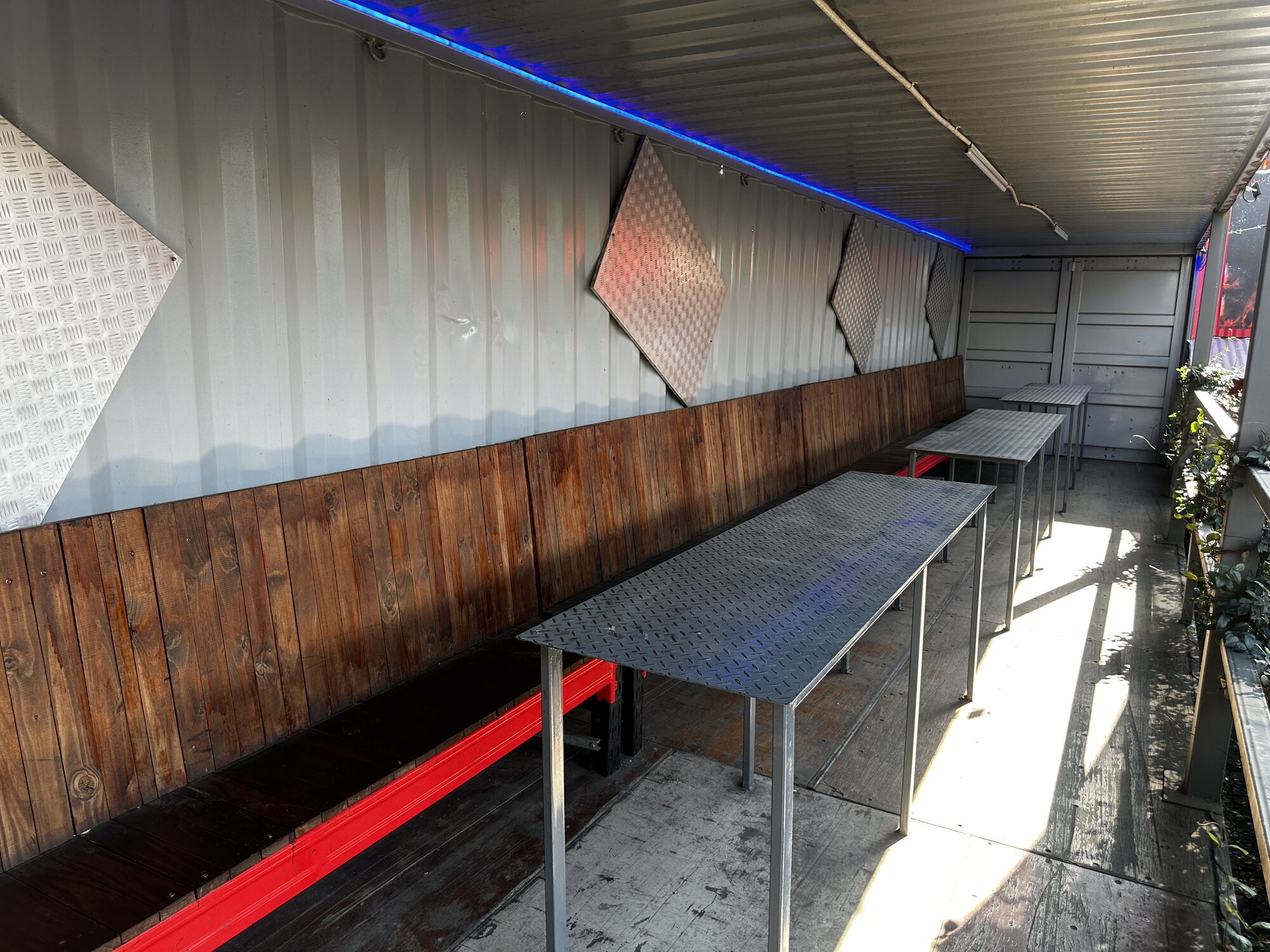 Covered container deck with wooden bench seating and high tables at Cheeky Tiger Midrand