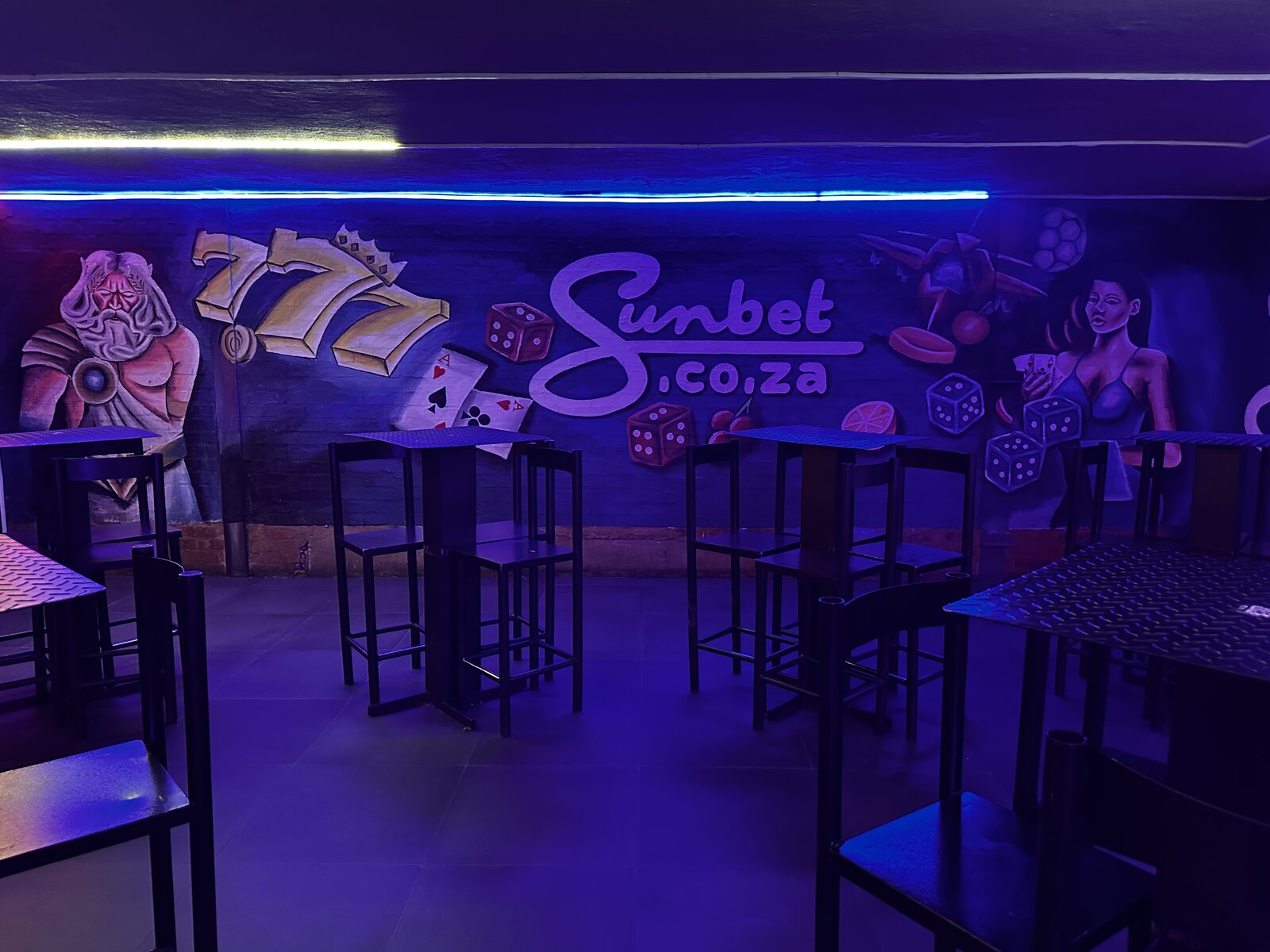 Sunbet mural wall with high tables and blue neon at Cheeky Tiger Midrand