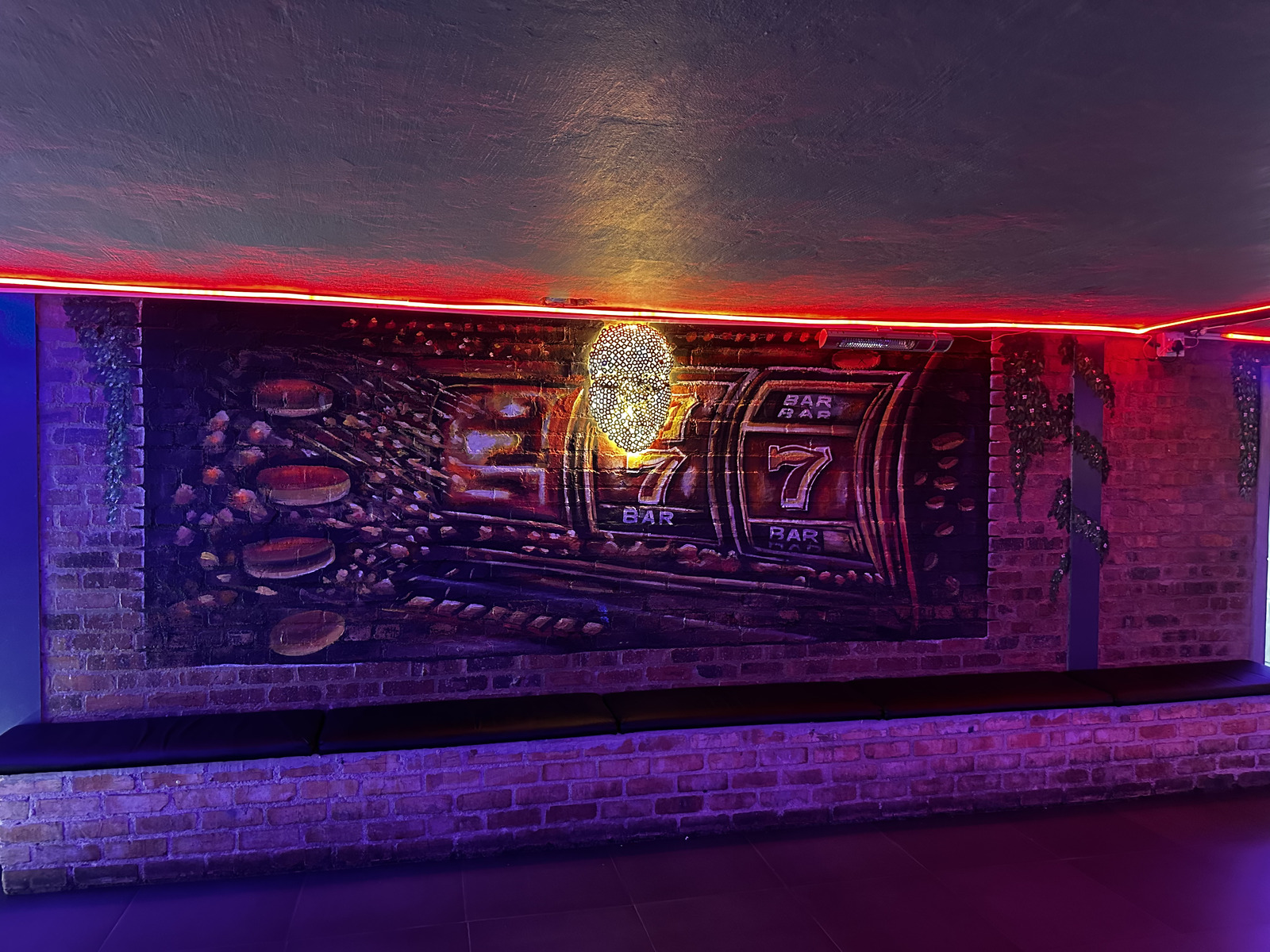 Hand-painted slot reel mural above bench seating at Cheeky Tiger Midrand