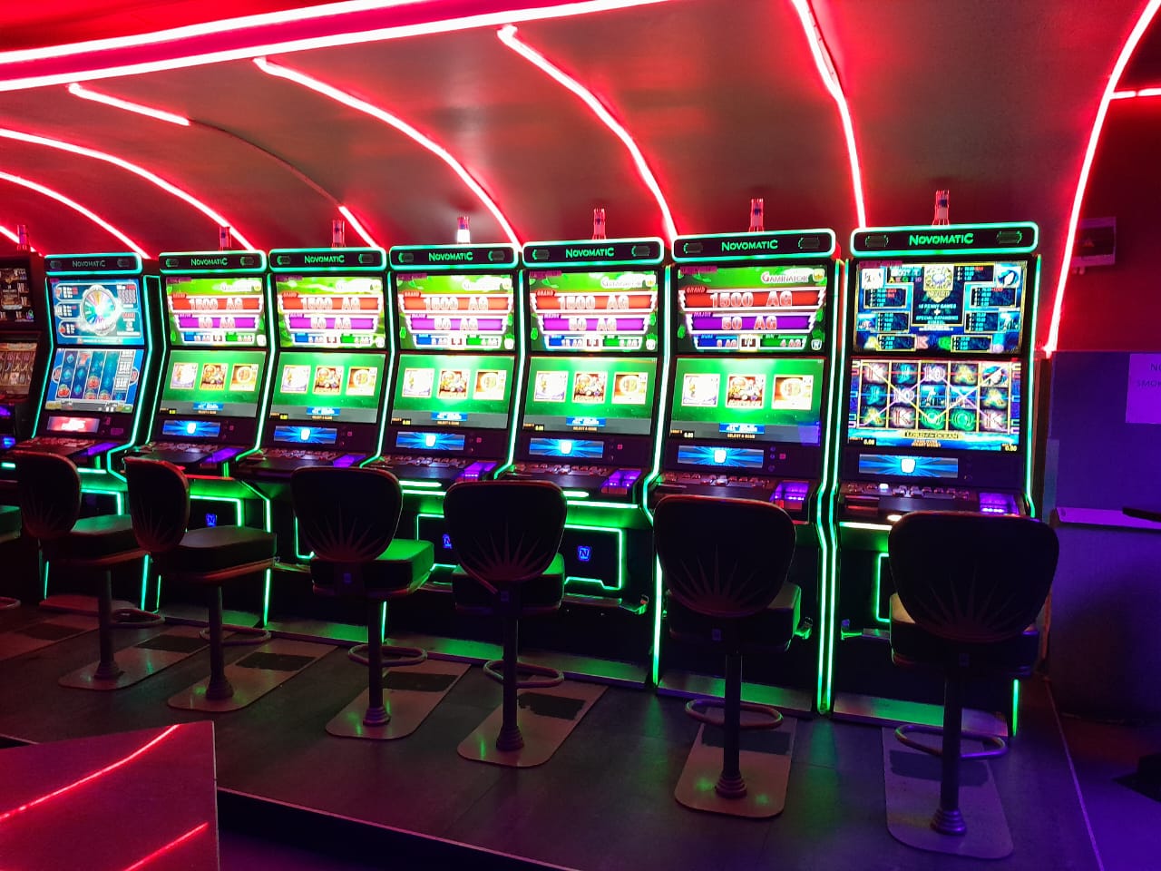 Novomatic slots row glowing under red neon arches at Cheeky Tiger Randburg