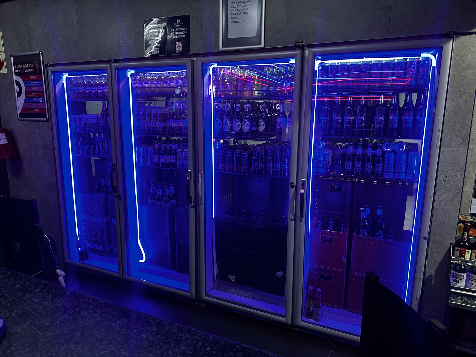 Fully stocked bar fridges glowing under blue neon at Cheeky Tiger Diepkloof Hotel