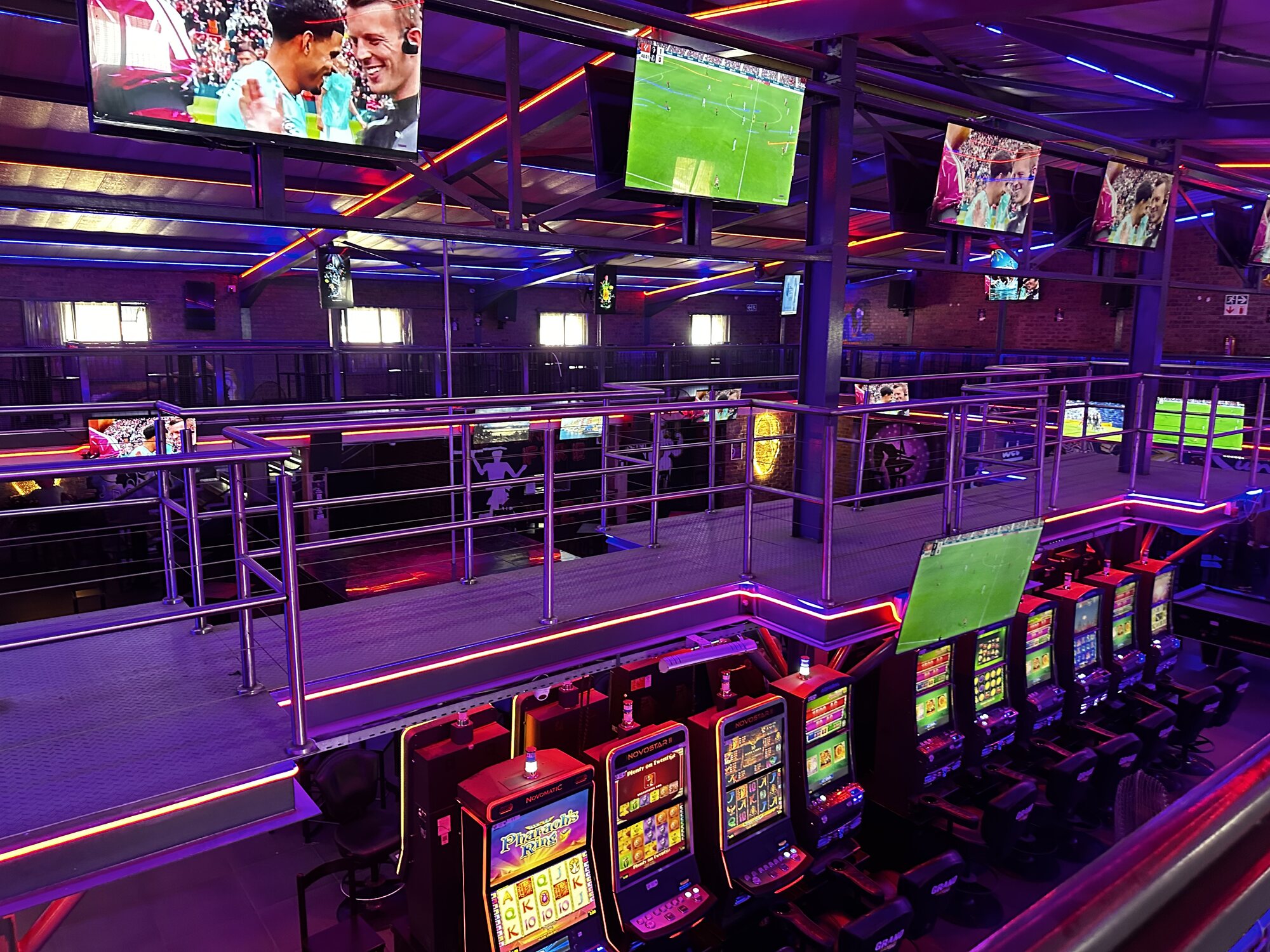 Novomatic slot machines and the big-screen sports wall seen from the mezzanine at Cheeky Tiger Midrand